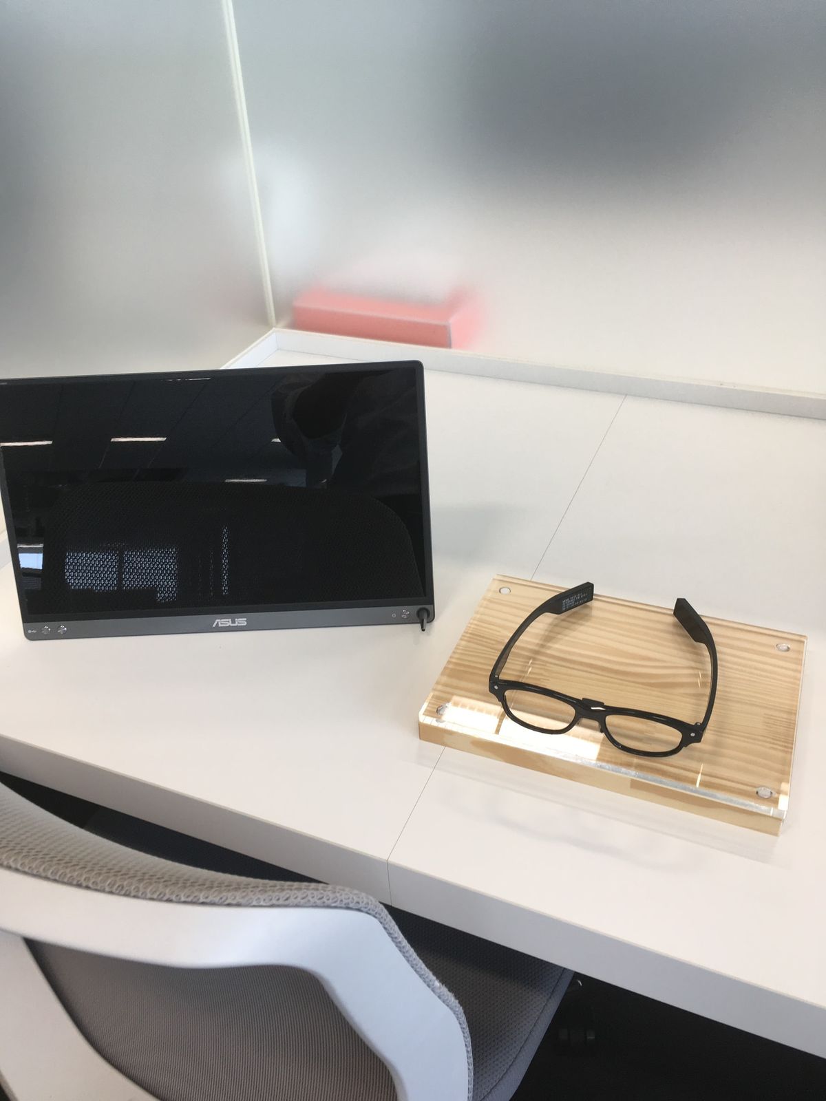 J!NS MEME glasses on a wooden tray next to a monitor