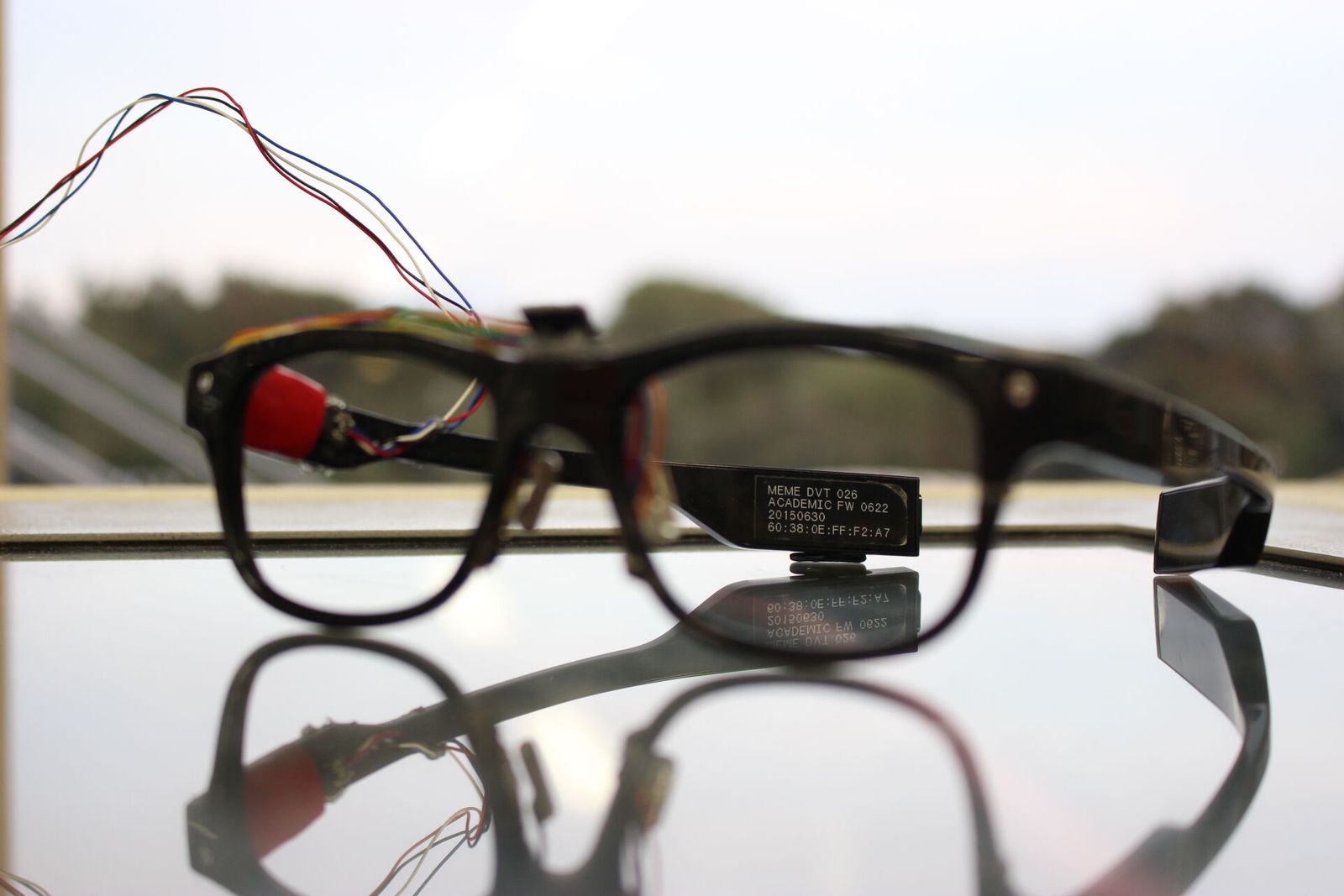 J!NS MEME academic prototype with sensor wiring on a glass table